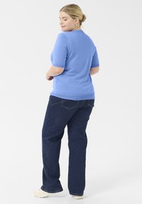 Suéter de manga corta azul claro combinado con jeans rectos de tiro oscuro. Textura suave, diseño sencillo y detalles de costura visibles.
