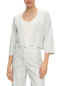 Lichtgrijze, cropped cardigan van een gestructureerde, glanzende stof met driekwartmouwen. Gecombineerd met hoge witte jeans.