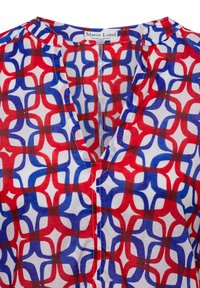 Bluse mit rot-weiß-blauem Muster und V-Ausschnitt, die ein geometrisches Design aufweist, aus weichem Stoff gefertigt ist und sichtbare Nähte entlang der Kanten hat.