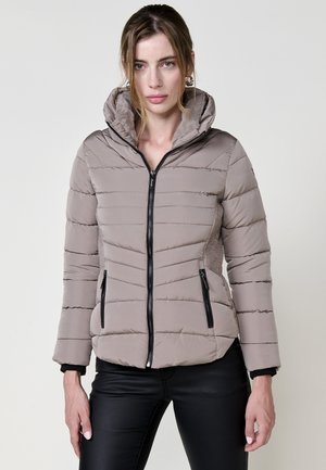 Chaqueta acolchada color topo con cierre frontal, capucha y dos bolsillos laterales con cremallera. Presenta una textura suave con detalles en negro y costuras horizontales.