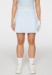 Vaaleansininen laskostettu golfhame, jossa on teksturoitu kuvio, joustava vyötärö, jossa on valkoiset raidat, yhdistettynä valkoisiin urheilukenkään ja sukkiin.