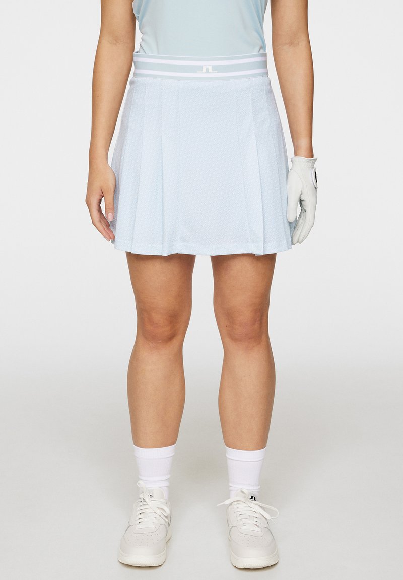 Vaaleansininen laskostettu golfhame, jossa on teksturoitu kuvio, joustava vyötärö, jossa on valkoiset raidat, yhdistettynä valkoisiin urheilukenkään ja sukkiin.