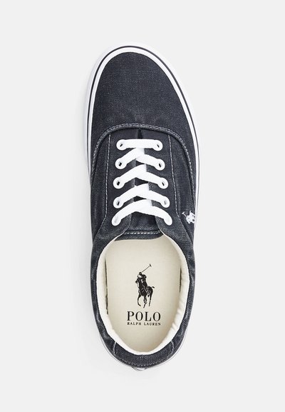 Σκούρο μπλε καμβάς αθλητικό παπούτσι με λευκές κορδόνες και καουτσούκ σόλα. Περιλαμβάνει λογότυπο στο εσωτερικό και αντίθεση λευκή ρέντα γύρω από τις άκρες.