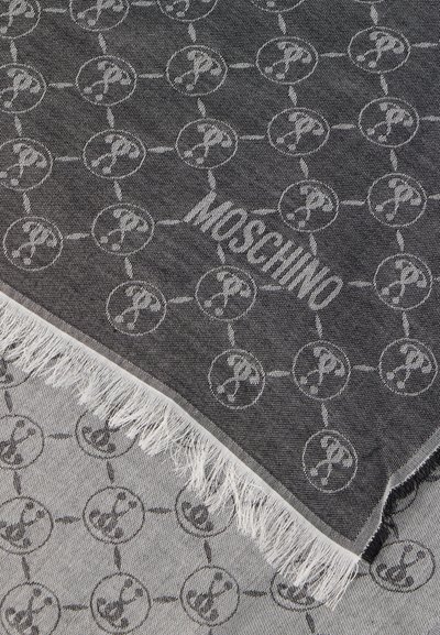 Šedý tkaný šál so vzorom opakujúcich sa kruhových log a strapcami na okrajoch. Názov značky "Moschino" je výrazne zobrazený.