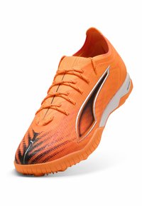 Orangene Sport Schuhe mit strukturiertem Mesh-Obermaterial, kontrastierenden schwarzen Akzenten, flachen Schnürsenkeln und langlebiger Gummisohle. Geeignet für Turf-Oberflächen.