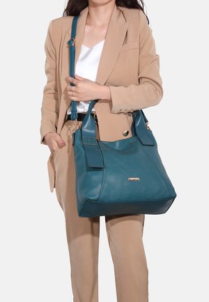 Handtas van groenblauw leer met een gestructureerde vorm, twee korte handvatten en een afneembare schouderriem. Heeft een metalen logodetail.