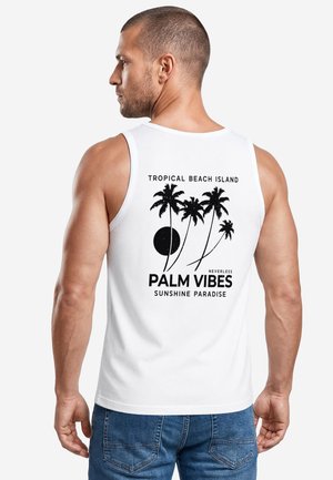 Mann trägt ein weißes Tanktop mit schwarzer Palme-Grafik und dem Text "Tropical Beach Island Palm Vibes Sunshine Paradise" auf dem Rücken.