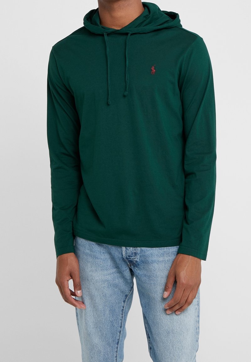 Grön långärmad hoodie i mjukt tyg, med en framficka i kangurostil, dragskor och en liten broderad logotyp på bröstet.