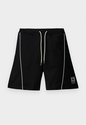 Short noir avec passepoil vertical blanc, cordon blanc à la taille élastique et petit logo Hugo près de l'ourlet inférieur sur la jambe droite.
