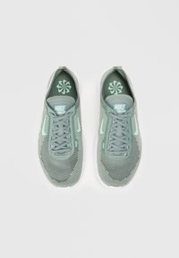 Grønne mesh Nike Free sneakers med matchende snørebånd, struktureret overflade, grå accenter og en hvid gummisål. Flad, non-profile visning.