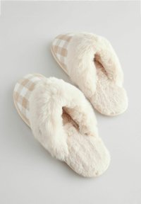 Tossut, joissa on pehmeä, beige-valkoinen ruudullinen kuvio päällisessä ja ylellinen valkoinen vuori. Tasapohjainen muotoilu.