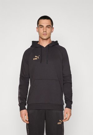 Svart hettegenser med kengurulomme, med en gull "KING" logo og Puma-emblem. Mykt stoff med teksturert mønster på ermene.