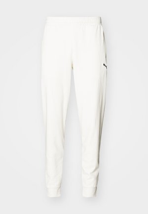 Pantalones de chándal blancos de algodón con una cinturilla elástica, piernas ajustadas y un pequeño logo de Puma en negro en el lado izquierdo. Textura suave.