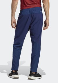 Marine sportieve broek met elastische tailleband, taps toelopende pasvorm en contrasterende textuurpanelen. Gecombineerd met zwarte sportschoenen.