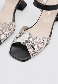 Sandalias de tacón negro con parte superior de imitación de piel de serpiente, detalles de corte, y una correa ancha con un diseño de nudo en la parte frontal.