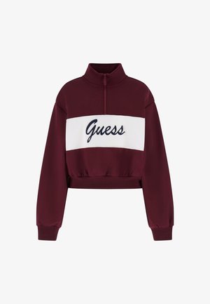 Sweat-shirt court bordeaux avec un col montant, arborant une bande blanche avec le logo "Guess" en bleu marine, ainsi qu'une taille et des poignets élastiques.