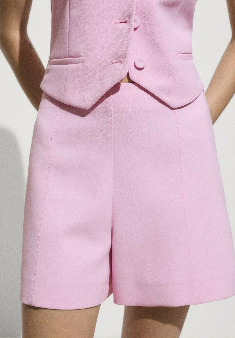 Pantaloni scurți roz, croiți, dintr-un material neted, cu talie înaltă, linii curate și detalii de cusătură minime pentru un aspect elegant.