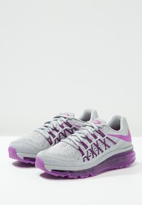 Baskets de course Nike Air Max gris clair et violet avec des lacets tissés et des semelles rembourrées, présentées côte à côte sur une surface blanche.