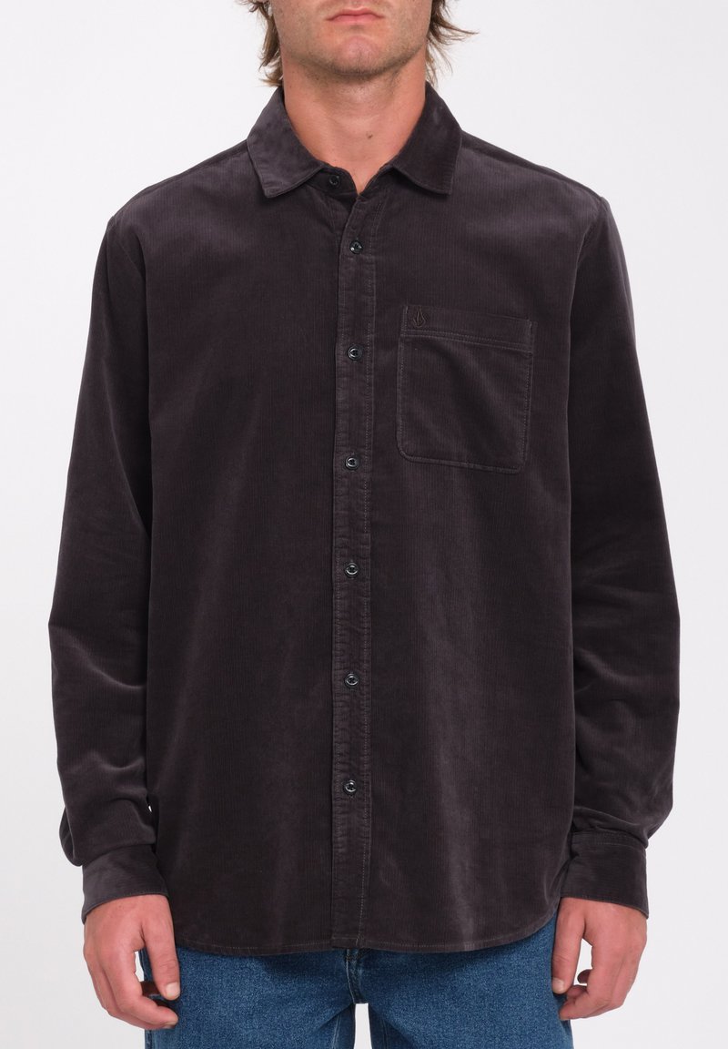 Chemise en velours côtelé, gris foncé, à boutons avec un col pointu, poche poitrine unique et boutons noirs. Manches longues avec poignets à boutons.