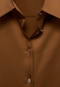 Brown collared shirt with a V-neck opening and three visible shiny metallic buttons fastened along the front center.