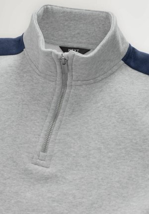 Grå pullover med design med halvlynlås, med marineblå skulderdetaljer. Blød tekstur, minimale syninger og et mærke indeni kraven.