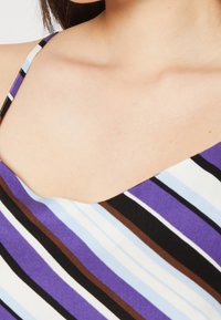 Abito a righe viola e blu con spalline sottili. Presenta un collo a barca e righe di varie larghezze in bianco, nero e marrone.