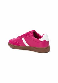Zapatillas sinteticas rosas con un acabado suave, que presentan rayas laterales blancas, punta redonda y una suela de goma marrón.
