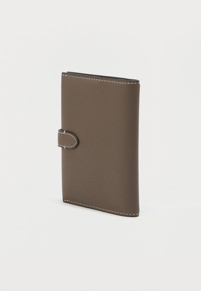 Καφέ δερμάτινο πορτοφόλι με υφασμάτινη επιφάνεια, που διαθέτει λευκή ραφή και κλείσιμο με κουμπί, σχεδιασμένο σε κάθετη ορθογώνια μορφή.