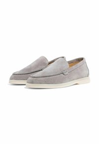 Een paar grijze suède instaploafer met witte rubberen zolen, in een hoek geplaatst om de binnen- en buitenzijde te laten zien tegen een witte achtergrond.