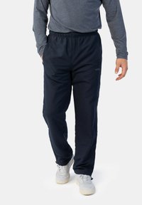 Marinefarbene Sporthosen aus einem glatten Stoff mit einem elastischen Bund, ausgestattet mit Seitentaschen und Reißverschlüssen an den Knöcheln zur Anpassung.