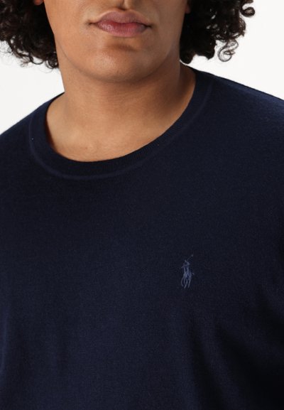 Tengerészkék crew-neck pulóver puha anyagból, diszkrét logóval hímzéssel a mellrészen és klasszikus, testhezálló fazonnal.