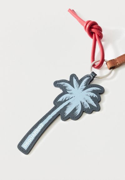 Porte-clés avec un design de palmier bleu portant l'inscription "DSQUARED2", attaché à un anneau en argent et une sangle nouée rouge sur fond blanc.
