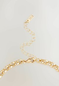 Armband i guldkedja med stora ovala länkar med en glänsande yta, inklusive en kattklor lås och en förlängningskedja för justerbar längd.