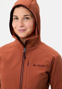 Bruine zip-up jas met een capuchon, gemaakt van een gestructureerde stof en met een klein logo op de borst. Inclusief een met rits afsluitbare zak aan de voorkant.
