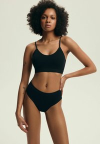 Czarny zestaw biustonosza i majtek z wysokim stanem; gładki materiał, minimalistyczny design, regulowane ramiączka, bezszwowe krawędzie, brak widocznych elementów metalowych, miękka faktura.