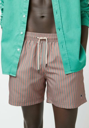 Costumi da bagno a righe colorate con un motivo grigio e rosa, vita con cordino e un piccolo logo, abbinati a una camicia verde con bottoni.