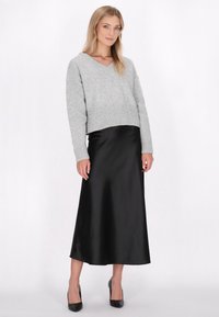 Szary, dziany sweter z dekoltem w kształcie litery V, w połączeniu z elegancką, czarną, satynową spódnicą maxi, która prezentuje gładką fakturę i klasyczny krój.