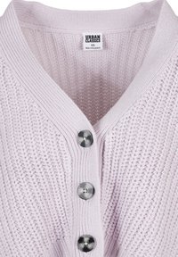 Lys rosa strikket cardigan med V-hals, som har fire runde, metalliske knapper og ribbestruktur langs kragen og knappestolpen.