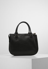 Sac à main en cuir noir de forme arrondie, avec deux poignées supérieures et fermeture éclair. Présente des coutures discrètes et des accents métalliques.