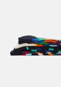 Chaussettes colorées à motifs empilées en couches ; les matériaux incluent un mélange de coton. Présente des motifs géométriques variés dans des teintes vives sur un fond sombre.