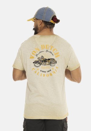 T-shirt court beige clair à manches courtes avec un graphique de moto vintage en noir et jaune au dos, et des détails d'ourlet effiloché.