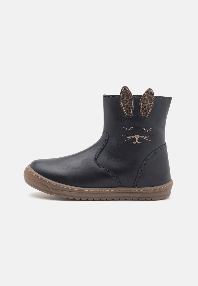 Botas negras de cuero hasta el tobillo con suelas de goma marrón, que presentan orejas con estampado de leopardo y detalles faciales bordados en la parte delantera.