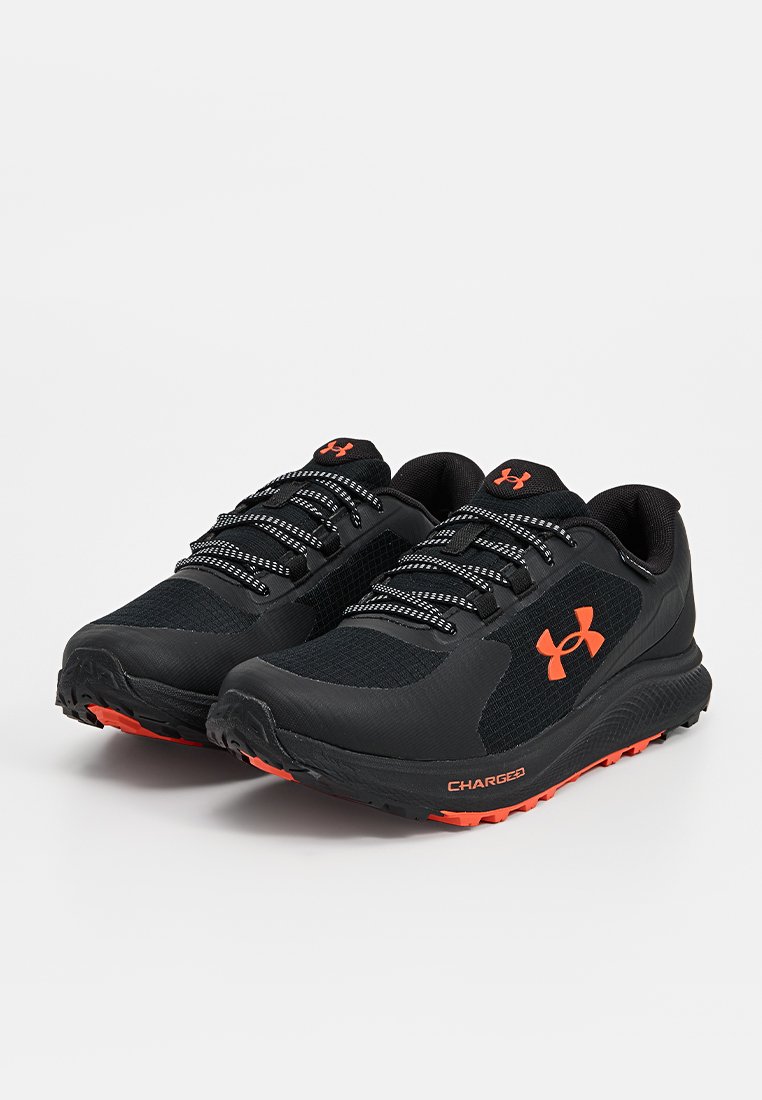 Chaussures de sport noires en mesh et matériaux synthétiques, accents orange, semelles épaisses en caoutchouc et lacets réfléchissants pour une meilleure visibilité.