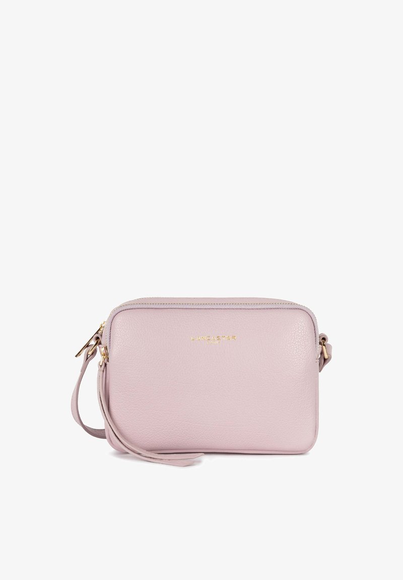 Sac bandoulière en cuir rose clair avec logo doré, fermeture éclair et une sangle de poignet amovible. Texture lisse avec forme rectangulaire.