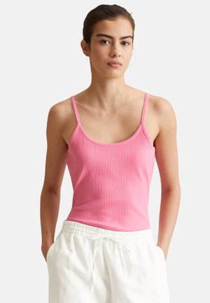 Pink ribbed tank top with thin straps, featuring a scoop neckline and a fitted design. Paired with white drawstring pants.