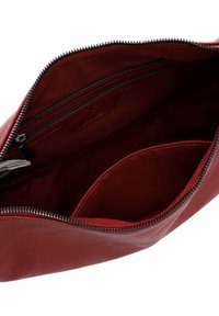 Red leather handbag interior with smooth texture, single compartment, a zippered pocket, and silver zipper detail.