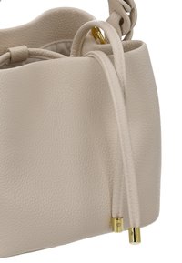 Bolso tipo cubo de cuero color durazno con acabado texturizado, que presenta una forma redondeada, asas ajustables y detalles en hardware dorado.