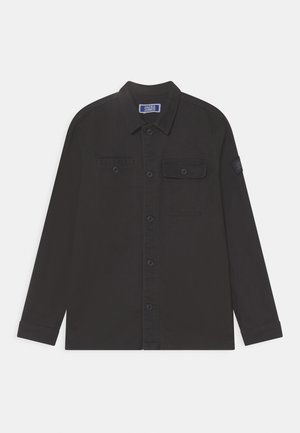 Camisa negra de manga larga con botones, dos bolsillos en el pecho, uno de solapa y cuello, mostrada extendida sobre un fondo blanco.