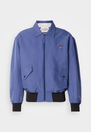 Μπλε μπουφάν τύπου bomber με φερμουάρ μπροστά, δύο λοξές τσέπες και μαύρα ριμπ μανίκια και τελείωμα. Διαθέτει κεντημένη λεπτομέρεια στέμματος στο στήθος.