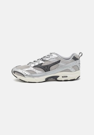 Silver running shoe with mesh upper, black accents, padded collar, and thick sole. Features lacing and patterned texture for breathability.